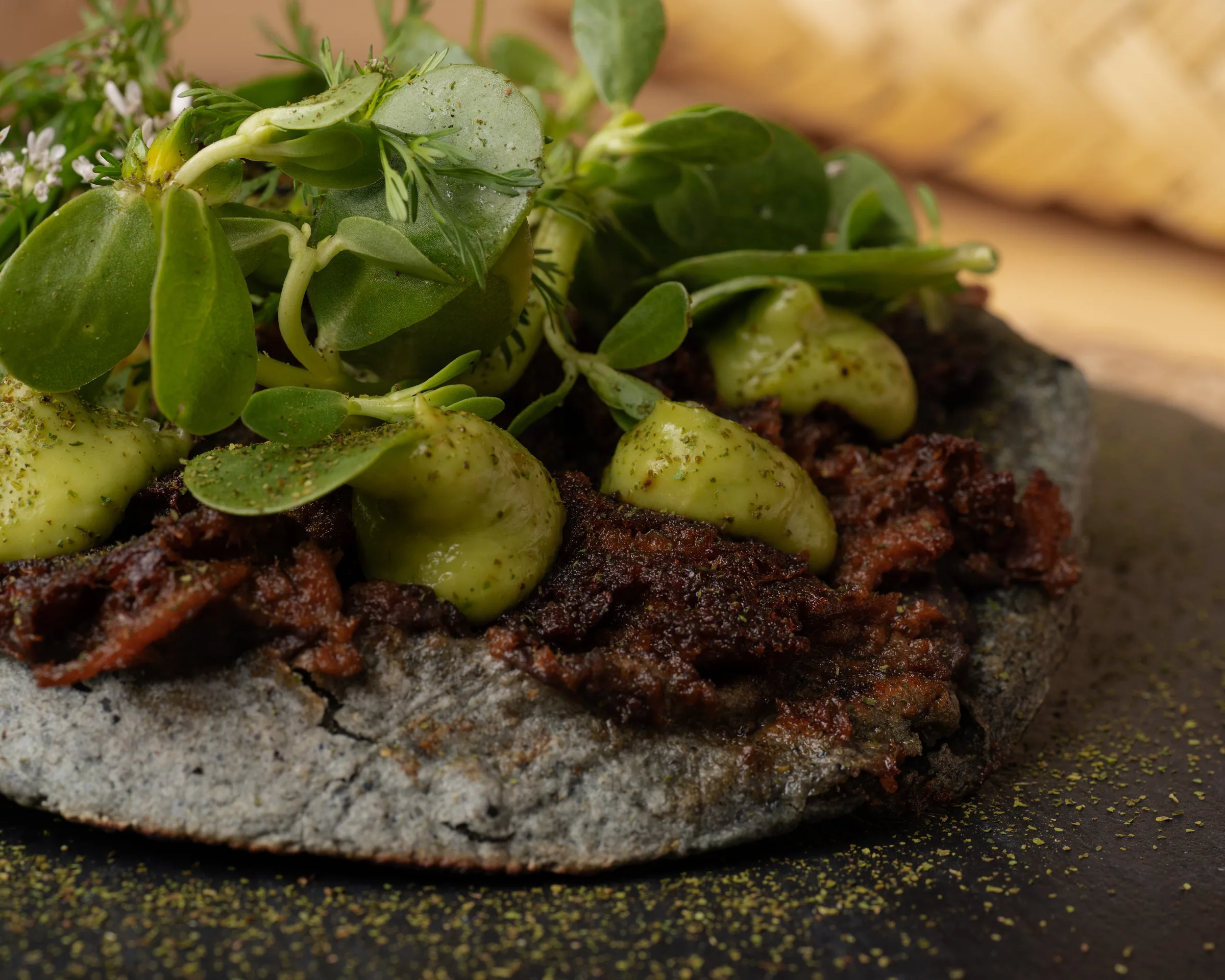 Detalle de carne, aguacate y hojas frescas sobre una tortilla.