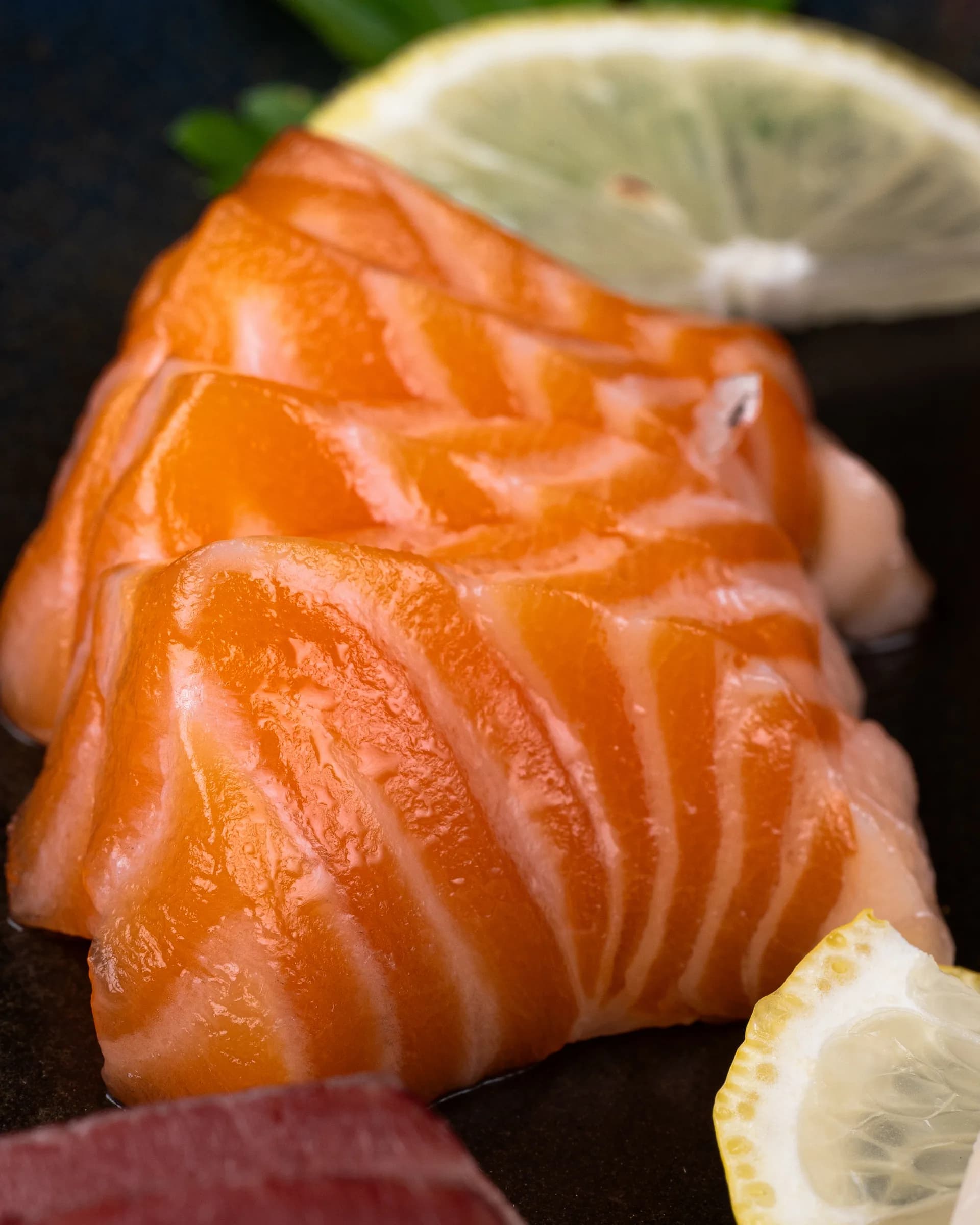 Cortes de salmón con una rodaja de limón al fondo.