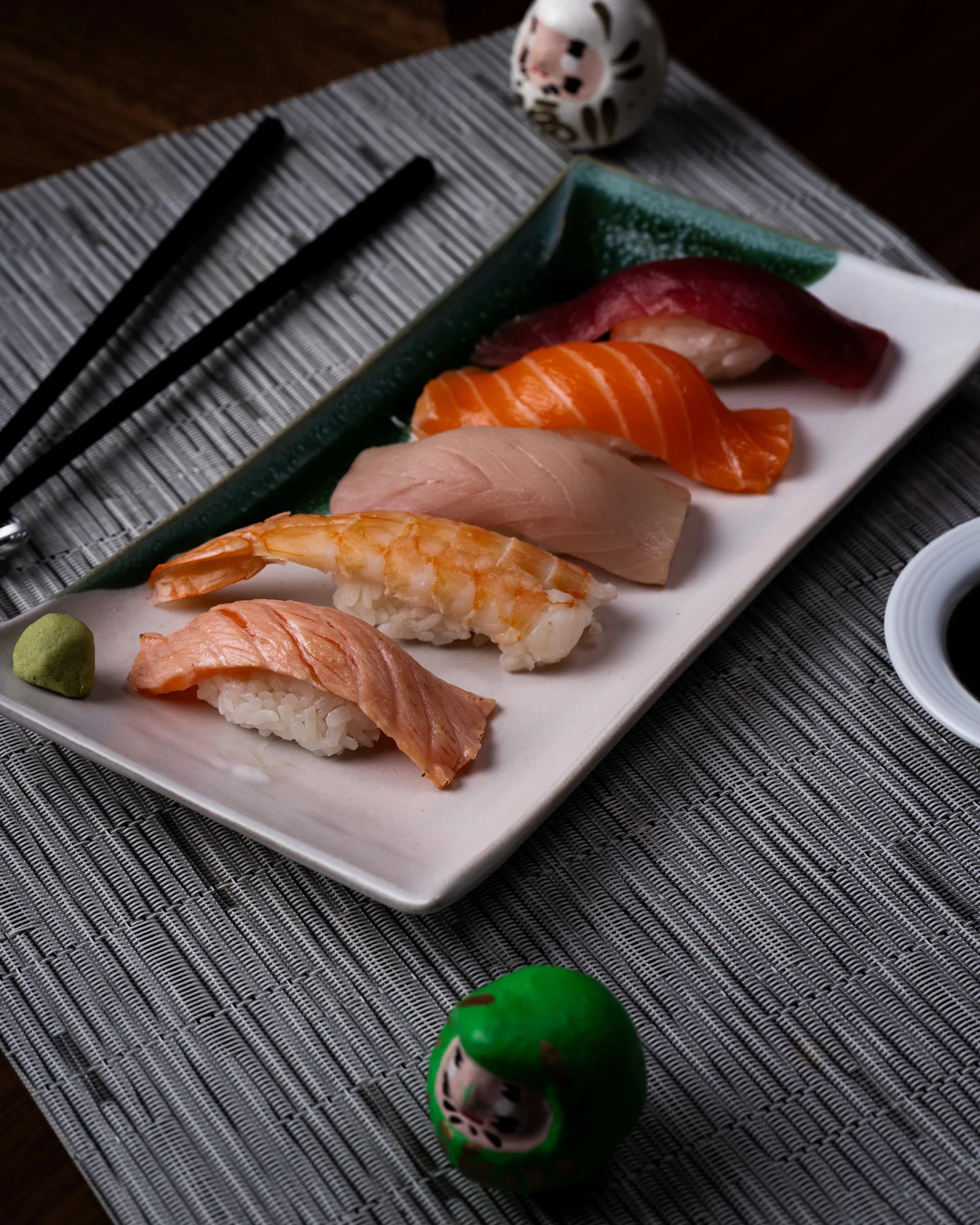 Plato de nigiri fotografiado en diagonal sobre una mesa.